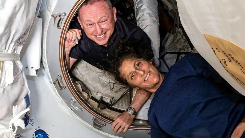 Dois astronautas, um homem e uma mulher no interior de uma espaçonave.