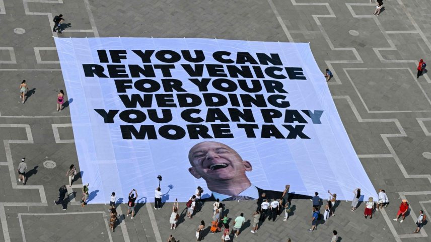 Ativistas do grupo ambiental internacional Greenpeace exibem uma faixa gigante com uma foto de Jeff Bezos e os dizeres: “Se você pode alugar Veneza para seu casamento, você pode pagar mais impostos.” (Foto: Stefano Rellandini / AFP)