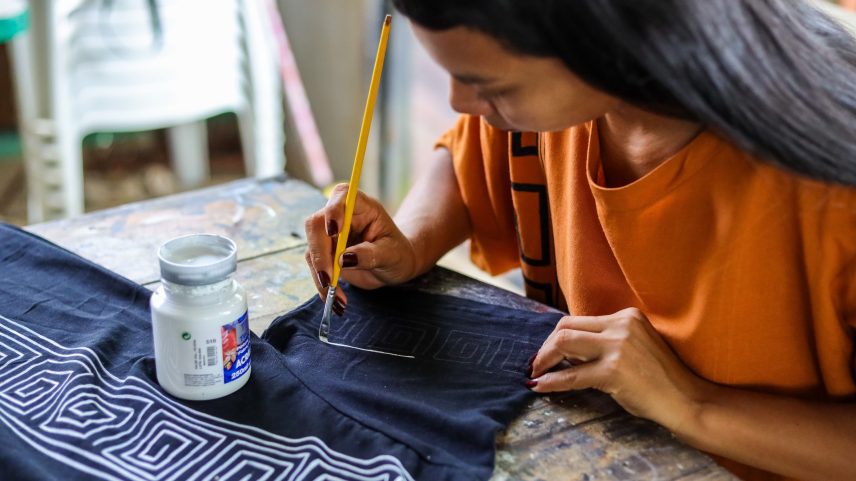 Erika Witoto desenha a estampa de tartaruga em uma blusa na sede do Ateliê Derequine em Manaus (Foto: Nathalie Brasil -12.mar.2025/Fundação Thomson Reuters)