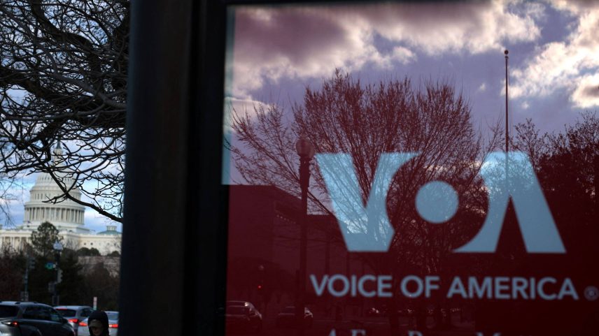 Placa de propaganda do programa Voice of America (VOA) em ponto de ônibus de Washington, EUA; ao fundo, Capitólio (Foto: ALEX WONG/Getty Images via AFP)