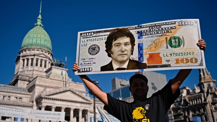 Apoiador de Milei carrega cartaz com a foto do presidente em uma nota de dólar (Foto: Luis ROBAYO/AFP)
