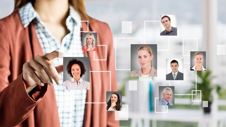 Uma mulher interage com uma tela virtual transparente contendo fotos de várias pessoas. As pessoas nas fotos têm aparência corporativa, como se fossem membros de uma equipe ou candidatos, enquanto ela no centro está selecionando uma dessas pessoas, sugerindo um processo de recrutamento. (Foto: USP Imagens)