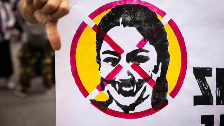 Protesters hold a sign with a photo of Prime Minister Paetongtarn Shinawatra crossed out at Victory Monument on June 28, 2025 in Bangkok, Thailand. Thousands of protesters gathered at Bangkok’s Victory Monument to demand Prime Minister Paetongtarn Shinawatra resign over a leaked phone call linked to a border dispute with Cambodia. It was the largest anti-government rally since 2023, adding pressure ahead of a possible no-confidence vote. (Foto: Lauren Decicca | Getty Images News)