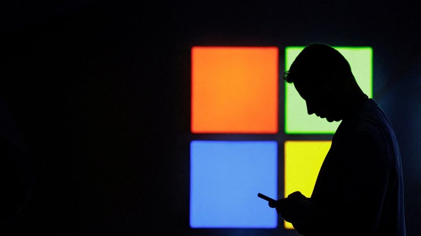 Um homem olha para o celular ao passar pelo estande da Microsoft na feira Mobile World Congress, em Barcelona, ​​Espanha, em 3 de março de 2025. (Foto: REUTERS/Bruna Casas/Foto de arquivo)