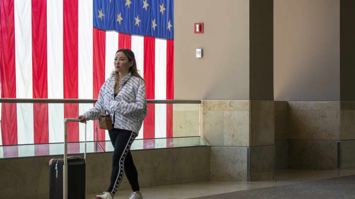 Um passageiro passa por uma enorme bandeira americana enquanto se dirige aos seus portões durante o feriado de Memorial Day no Aeroporto John Wayne, em Orange County, Santa Ana, CA, na quinta-feira, 26 de maio de 2022. (Foto: Allen J. Schaben | Los Angeles Times | Getty Images)