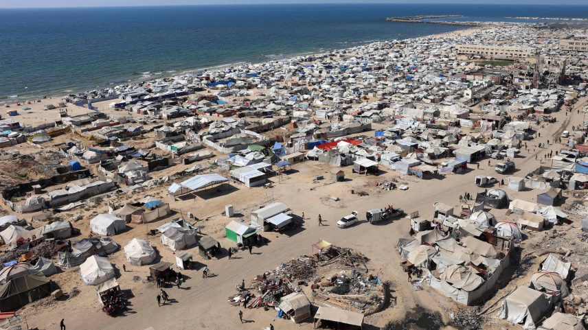 Tendas e abrigos de palestinos deslocados pelo conflito são vistos em um acampamento improvisado montado na praia, próximo ao porto de Gaza (Foto: Omar Al-Qattaa - 19,jul.25/AFP)