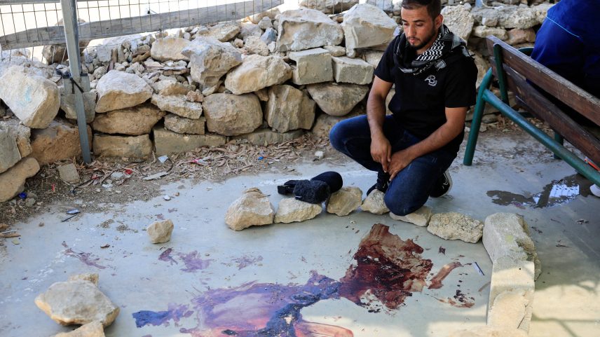 Homem em frente a mancha de sangue após colono israelense atirar em palestinos e matar colaborador de filme vencedor do Oscar (Foto: Mussa Qawasma/Reuters)