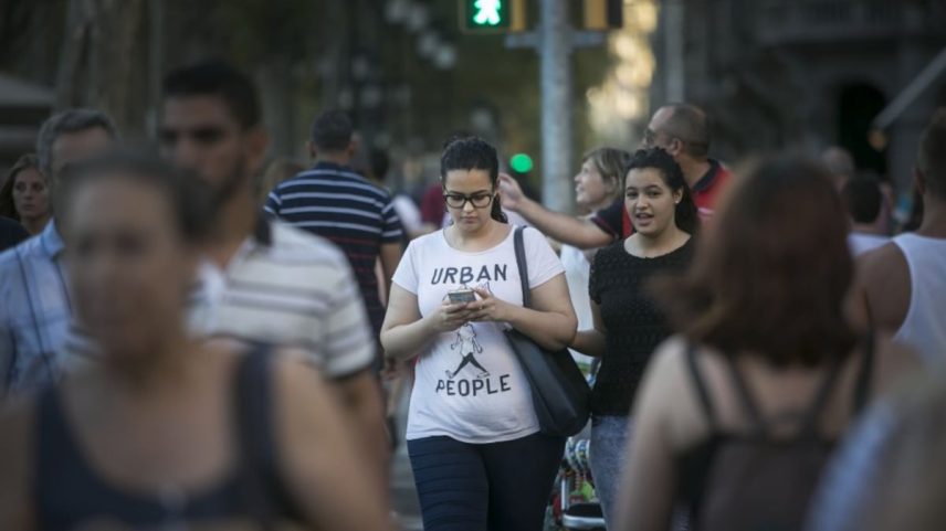 Uma mulher olha para o celular enquanto atravessa um passo de zebra. (Foto: Massimiliano Minocri)