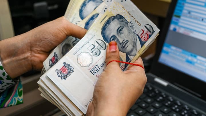 Um funcionário conta notas de moeda em dólar de Singapura no distrito financeiro de Raffles Place, em Cingapura, em 6 de outubro de 2022. (Foto: Roslan Rahman | Afp | Getty Images)