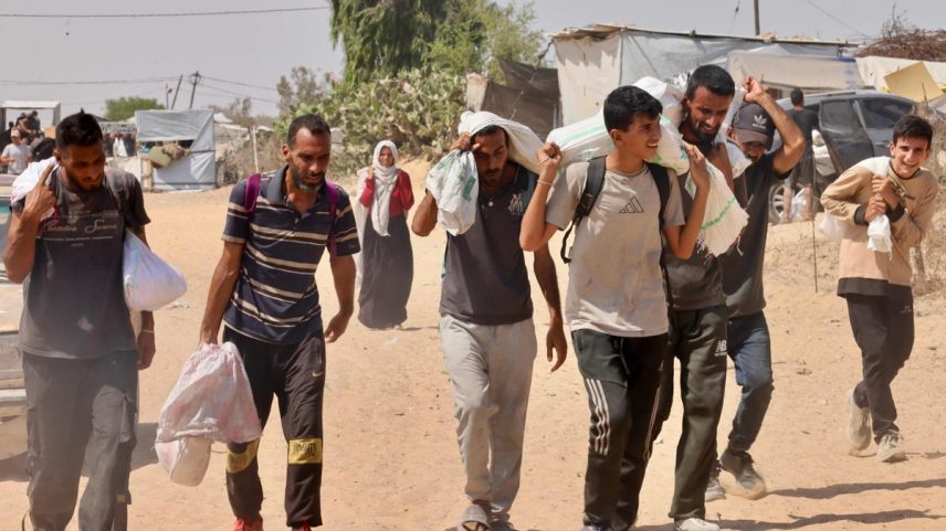 Palestinos carregam ajuda humanitária que receberam em Rafah, no sul da Faixa de Gaza (Foto: AFP)