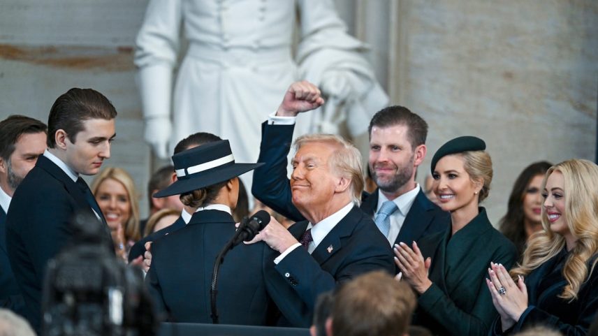 Donald Trump, com o punho levantado, no dia de sua posse em janeiro, com seus filhos Barron, Eric, Donald Jr. e Ivanka, e sua neta Kai, da esquerda para a direita. Com as costas voltadas, usando um chapéu, está Melania Trump. (Foto: Kenny Holston/AP)