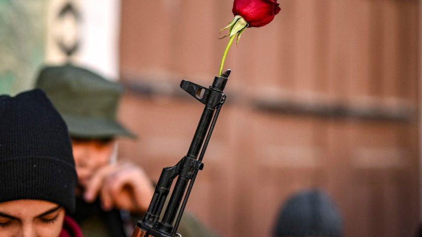 Uma rosa é colocada em um rifle de um combatente rebelde sírio antes das orações semanais muçulmanas de sexta-feira na mesquita Umayyad, em Damasco (Foto: Aris MESSINIS / AFP)
