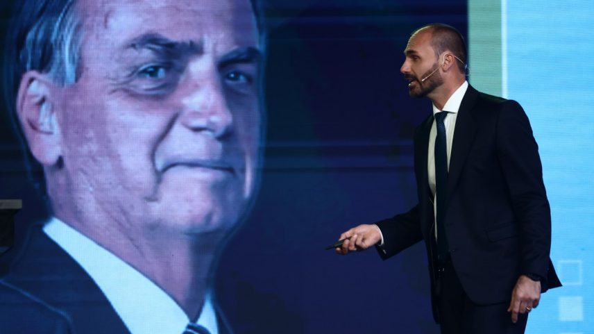 Eduardo Bolsonaro discursa ao lado de uma imagem de seu pai, o ex-presidente Jair Bolsonaro, durante a CPAC, evento da extrema direita, em Buenos Aires, Argentina - 04/12/2024 (Foto: Tomas Cuesta/Getty Images)