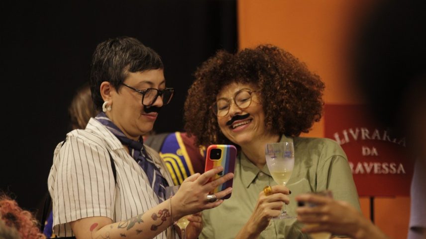 Natália Borges Polesso (com celular na mão) e Luciany Aparecida em sarau na Casa Toda Poesia (Foto: Alexandre Cassiano/ Agência O GLOBO)