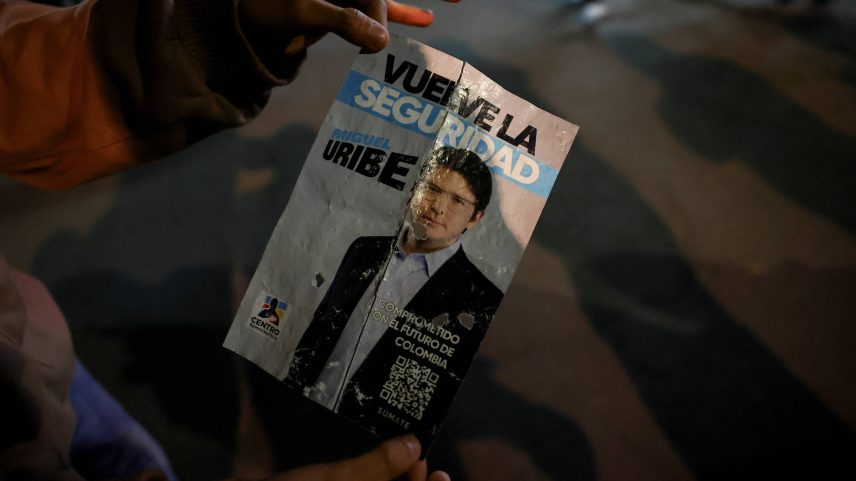 Pessoa segura cartaz de campanha onde senador colombiano Miguel Uribe, do partido de oposição Centro Democrático, foi baleado em Bogotá (Foto: Luisa Gonzalez - 7.jun.25/Reuters)