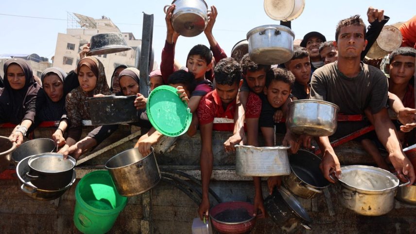 Palestinos recebem sopa de lentilha em um ponto de distribuição de alimentos na Cidade de Gaza (Foto: Omar AL-QATTAA / AFP)