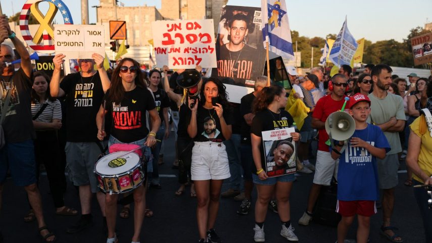 Manifestantes erguem bandeiras e fotos durante protesto contra o governo de Israel, em frente à casa do premiê Benjamin Netanyahu, pedindo ações para garantir a libertação de reféns israelenses mantidos pelo Hamas em Gaza. 07/08/2025 (Foto: Ahmad Gharabli/AFP)