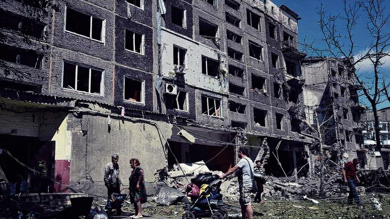Moradores locais observam prédio residencial fortemente danificado após ataque russo na região de Donetsk (Foto: Genya SAVILOV / AFP)