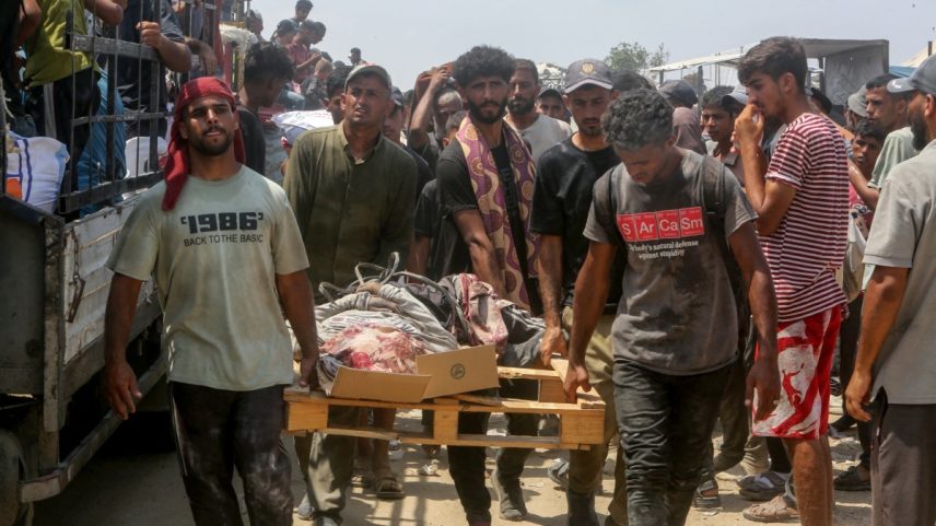 Pessoas carregam uma pessoa que foi morta durante um tumulto, quando palestinos deslocados invadiram caminhões que transportavam ajuda humanitária em Khan Yunis, no sul da Faixa de Gaza, em 9 de agosto de 2025 (Foto: AFP).