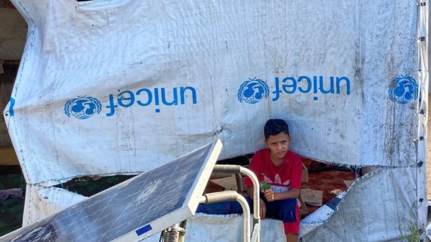 Menino senta ao lado de tenda em acampamento para palestinos deslocados em Khan Younis, no sul de Gaza (Foto: AFP)