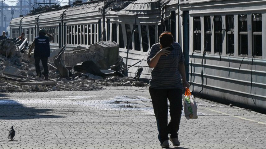 Moradora caminha ao lado de trem destruído em Lozova, na região ucraniana de Kharkiv (Foto: Genya SAVILOV / AFP)