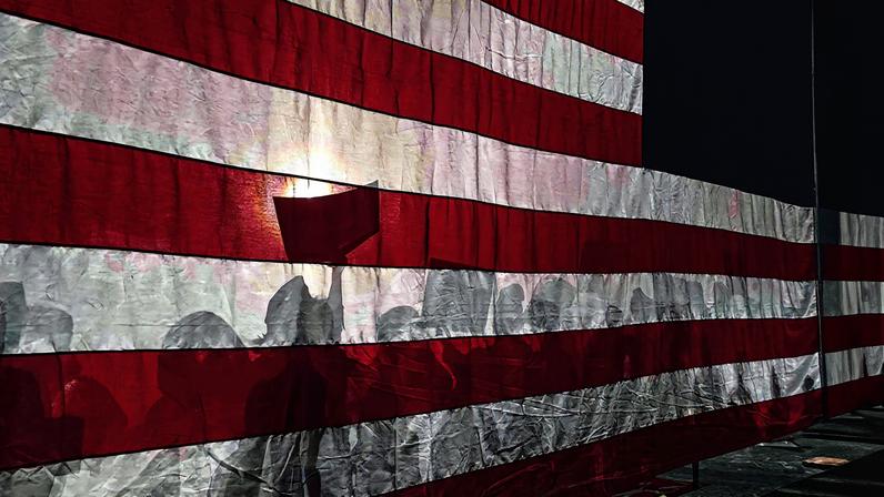 A bandeira dos Estados Unidos sob sombras de apoiadores republicanos em evento do partido, em New Hampshire (Foto: Joseph Prezioso - 21.jan.24/AFP)