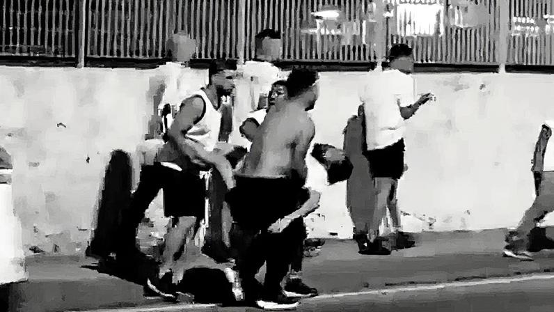 Torcedores carregam um homem ferido às margens da linha férrea em Oswaldo Cruz (Foto: Reprodução)
