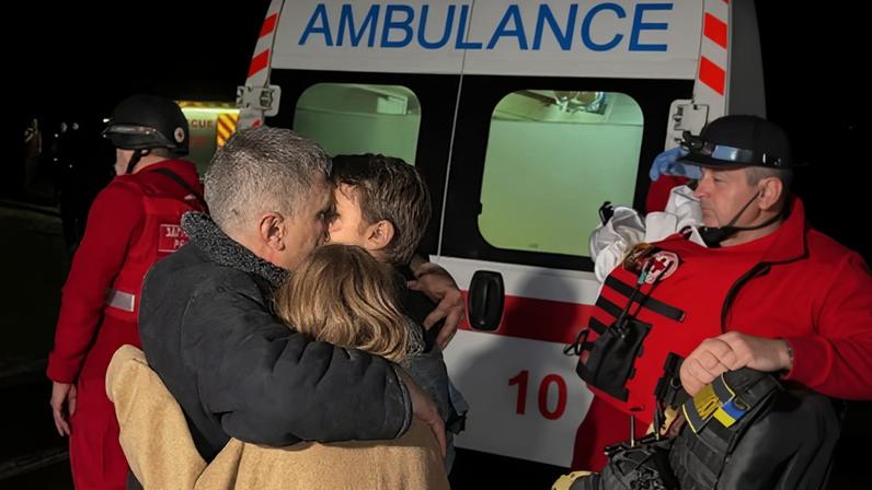 A father hugs his children after their mother was killed during a Russia drone strike in Kharkiv amid Russia's attacks on Ukraine.