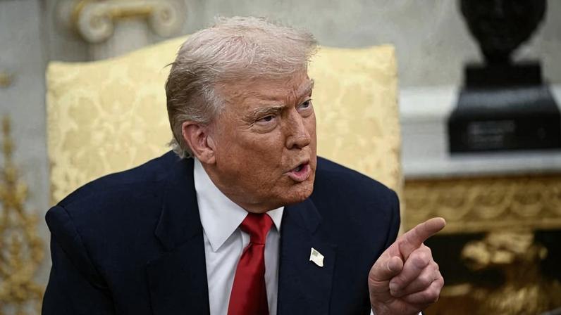 Donald Trump is seen pointing and talking while sitting in a chair in the Oval Office.