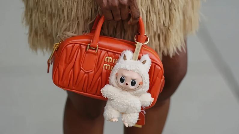 Uma mini bolsa de couro acolchoado Miu Miu laranja com detalhes em um Labubu de pelúcia creme durante a Semana de Moda de Copenhague