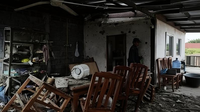Um guarda inspeciona uma casa evacuada que foi atingida pela artilharia cambojana no início da manhã, em uma vila próxima à fronteira entre a Tailândia e o Camboja, na província de Surin, em 11 de dezembro de 2025. Foto: Lillian SUWANRUMPHA / AFP