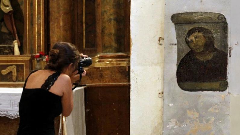 Turista fotografa o quadro 'restaurado' por Cecília Gimenez em 2012 – Foto: CESAR MANSO/AFP
