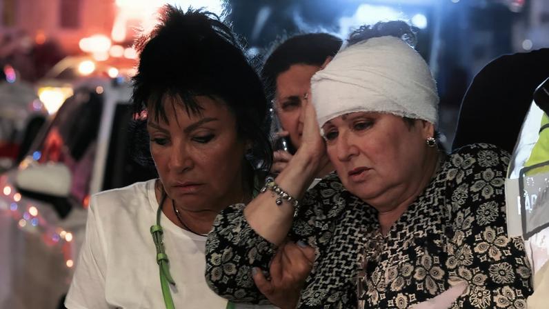 A woman with a bandaged head is taken to an ambulance after the deadly gun rampage on Bondi beach in Australia.