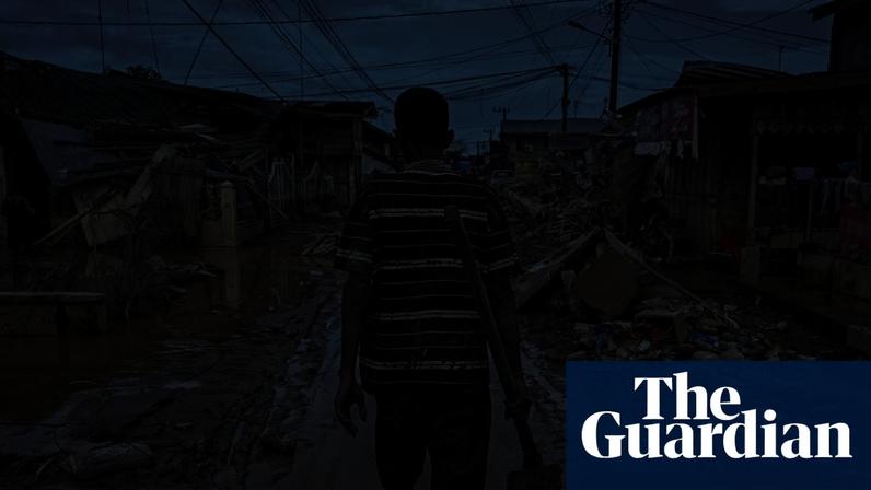 A man walks down a mud-covered street in Aceh Tamiang in Indonesia after flood waters receded. Photograph: Yt Hariono/AFP/Getty Images