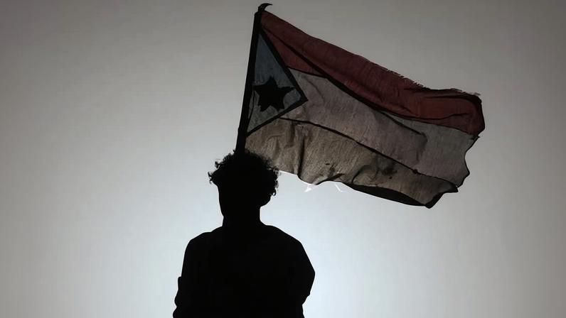 A person waves a South Yemen flag. Actions by separatists in Yemen have put pressure on the relationship between Saudi Arabia and the UAE.