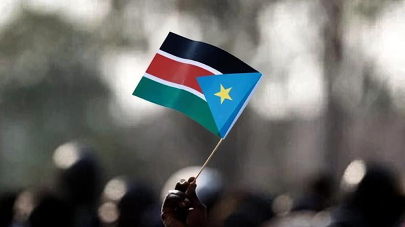 A person holds a flag of South Sudan.