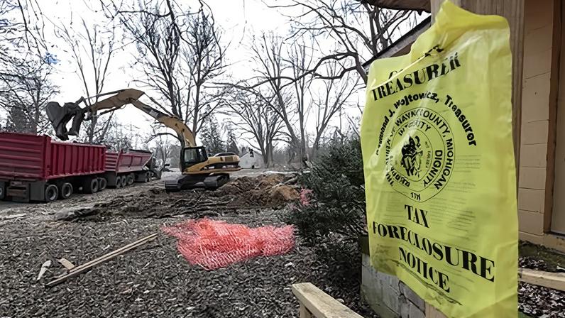 An excavator removes debris from a demolished house next to a house with a foreclosure notice in Detroit’s Brightmoor area on 24 March 2014.