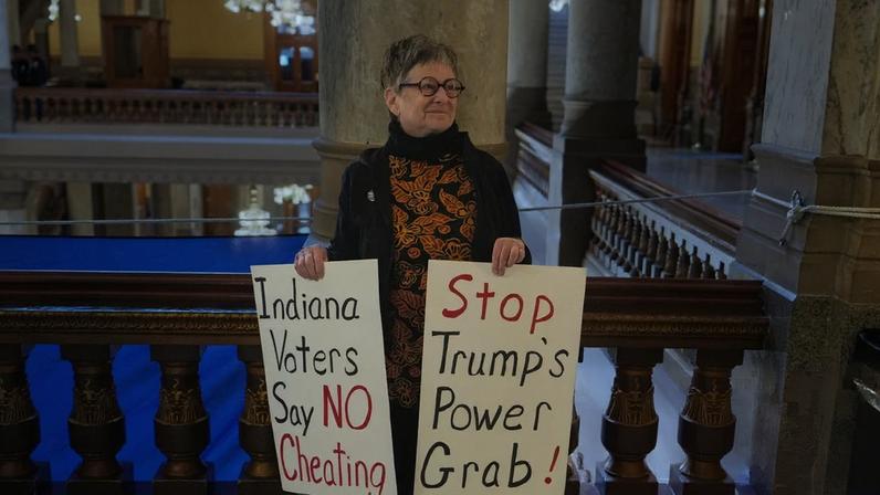 A protester holds signs outside the Indiana senate chamber in Indianapolis on Thursday.