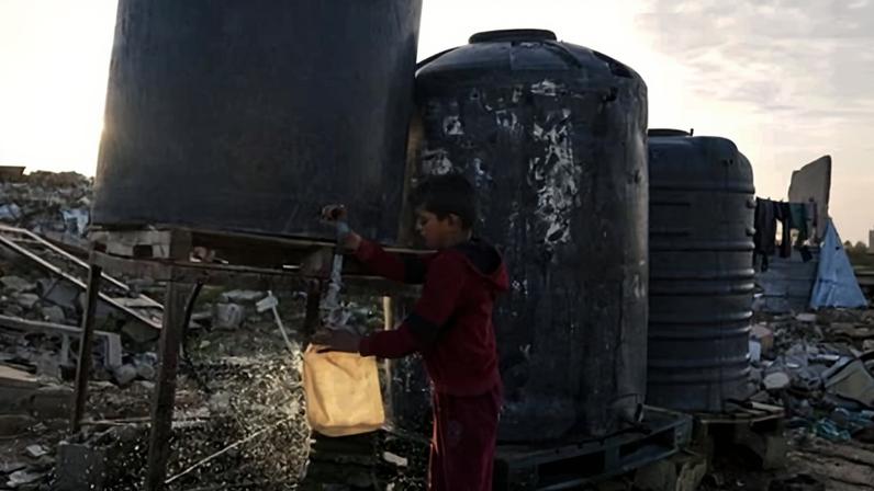A Palestinian boy collects water from a tank amid the rubble of destroyed buildings in Gaza City on Tuesday.