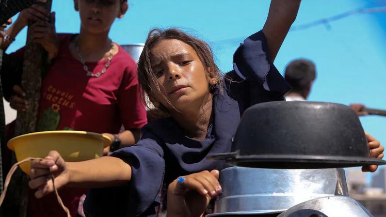 Palestinians wait to receive food from a charity kitchen, amid a hunger crisis, in Khan Younis
