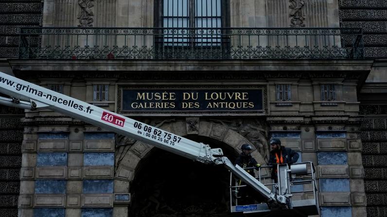 Workers install iron window guards on a window at the Louvre Museum in Paris.