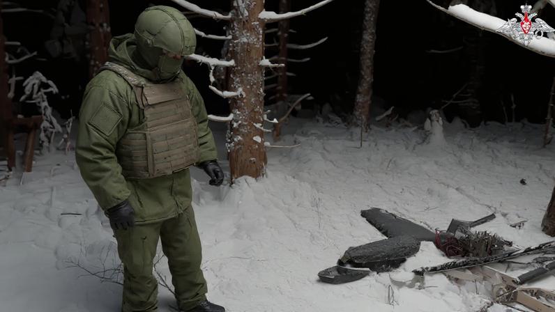 A Russian service member stands next to the remains of a drone, which, according to the Russian Defence Ministry, was downed during the repelling of an alleged Ukrainian attack on the Russian presidential residence in the Novgorod Region, in an unknown location in Russia, in this still image from a video released December 31, 2025.