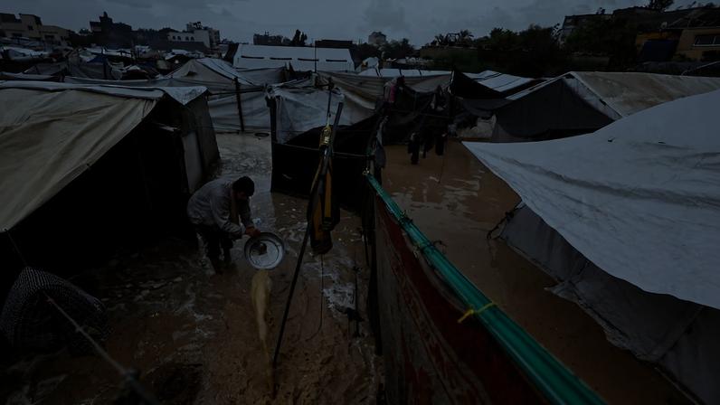 Un niño palestino camina por una zona inundada en un campamento en Deir al Balah, este viernes.