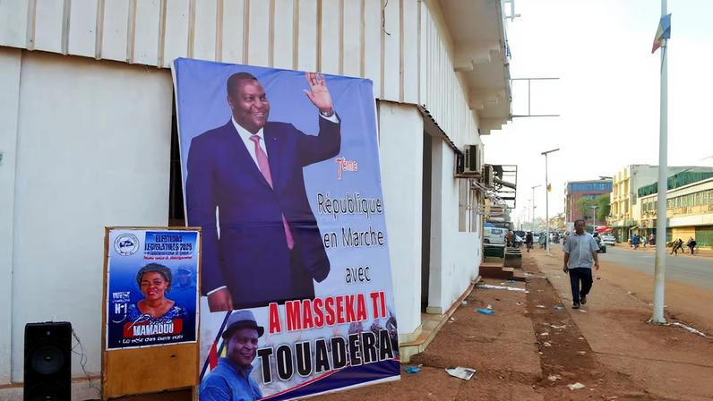 A man walks past a campaign billboard of President and presidential candidate Faustin-Archange Touadera, ahead of the presidential election scheduled for December 28, in Bangui