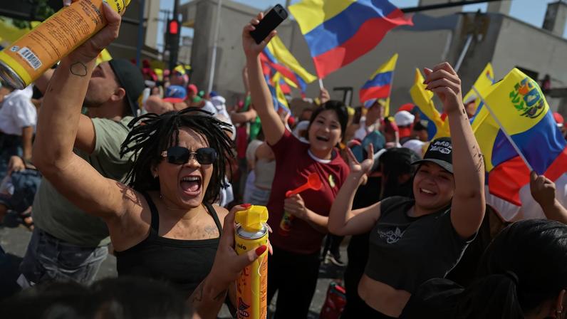 People wave Venezuelan flags and spray foam as they shout and smile in a large celebratory crowd.