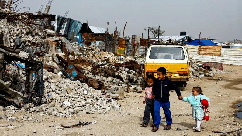 Palestinian children walk past the rubble of residential buildings destroyed during the war, in Gaza City, January 28, 2026. REUTERS/Mahmoud Issa