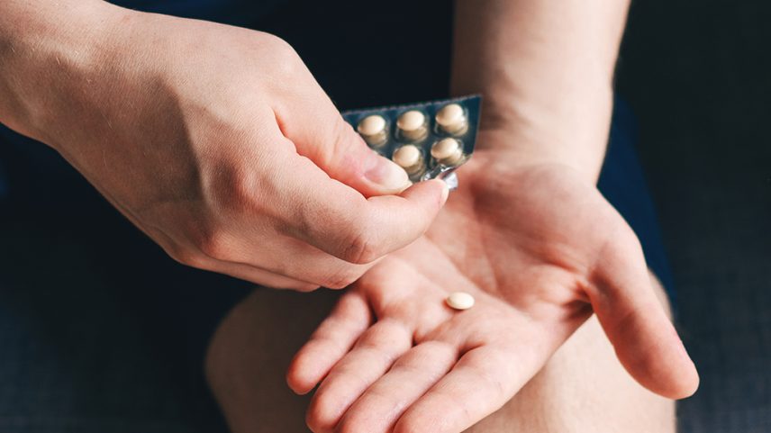 Imagem aproximada de uma pessoa segurando uma embalagem de remédios.