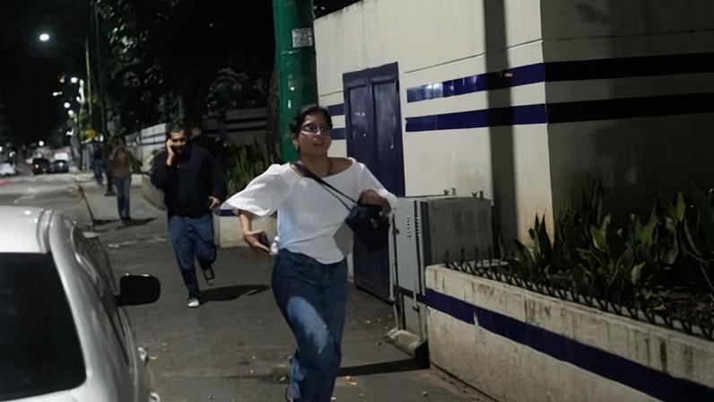 A woman and man run on a dark street in Caracas.