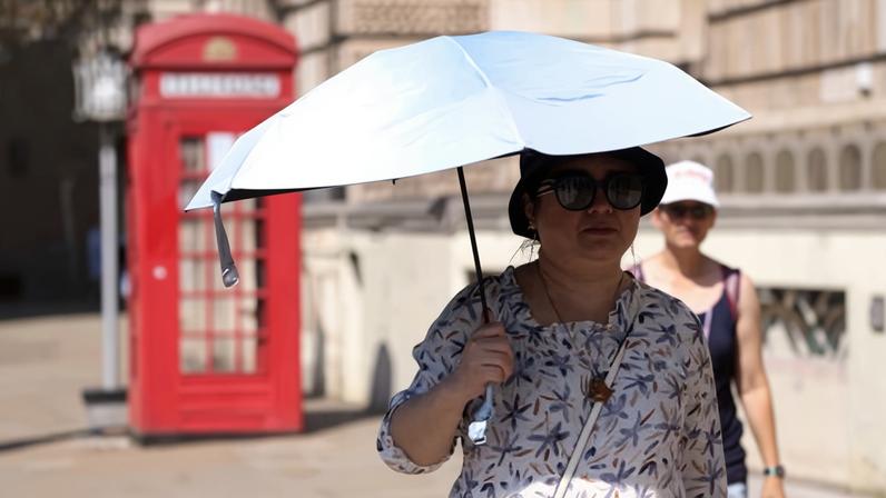 A woman shelters from the sun under an umbrella in London on 1 July 2025.