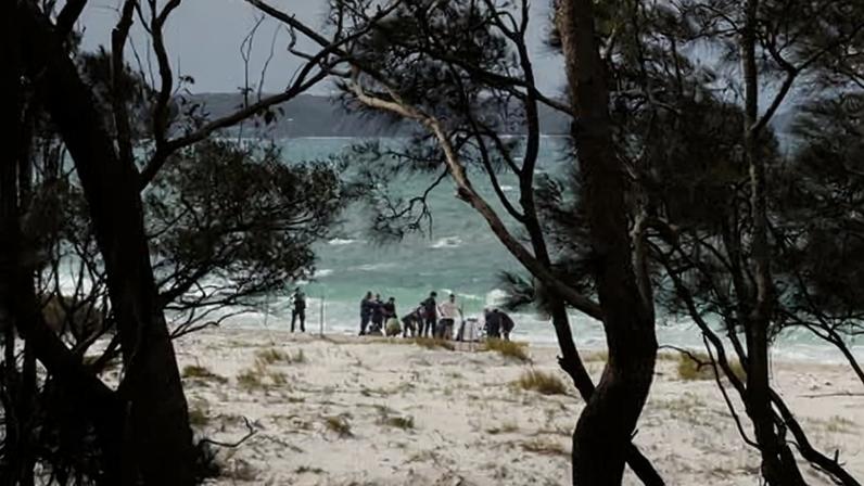 Police and paramedics gather on the beach at the location where a man was being treated after being pulled from the water at Greenpatch / Iluka Beach in Jervis Bay.